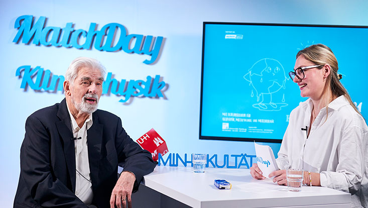 Ein junge Frau spricht in einem Studio mit dem Physik-Nobelpreisträger Klaus Hasselmann.